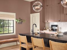 a kitchen with wooden chairs and an island in front of a window that has glass globes hanging from the ceiling