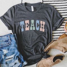 Teacher T Shirt, Pastel Teach Shirt, Teacher Shirt, Teacher Gifts, Elementary School Teacher Tee, Teach Tee Looking for more teacher/back to school apparel? Check these out: https://www.etsy.com/shop/TheGraphicPeach?ref=seller-platform-mcnav§ion_id=34195008 Our shop uses direct-to-garment printing to make our products. The design ink is sprayed on, then allowed to soak into the fibers of the garment. This process yields fine quality prints and a smooth finish on the garment. BELLA + CANVAS UNISE School Spirit Letter Print Top, Graphic Tee With Text Print For Teaching, Cotton T-shirt With Name Print For Teaching, Relaxed Fit Tops With Text Print For Teaching, Gray School Top With Letter Print, Gray Letter Print Top For School, Relaxed Fit Short Sleeve T-shirt For Teaching, School Apparel, Teach Shirt