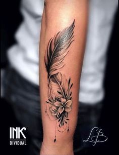 a black and white photo of a feather with flowers on its side tattoo by ink individual