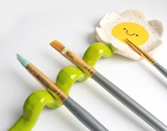 three green and white ceramic objects with paintbrushes in the shape of an egg