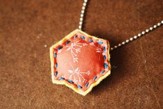 a red and blue piece of fabric hanging from a silver ball chain on a brown surface