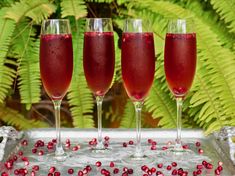 three wine glasses filled with red liquid and garnished with pomegranates