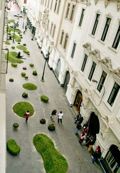 an aerial view of people walking on the sidewalk in front of buildings with green grass