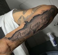 a man with a tattoo on his arm that says peace comes from behind the map