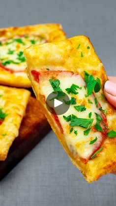 someone holding up a slice of pizza with cheese and parsley on it to eat