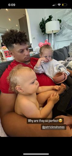 a woman sitting on top of a couch holding a baby and looking at a laptop