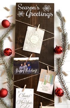 christmas cards hanging from clothes pins on a wooden board