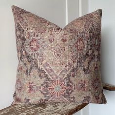 a pillow sitting on top of a wooden bench next to a white wall and door