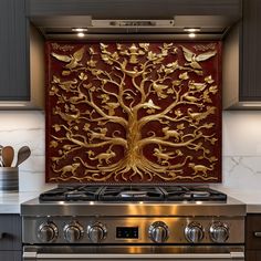 a stove top oven sitting next to a wall mounted art piece with a tree on it