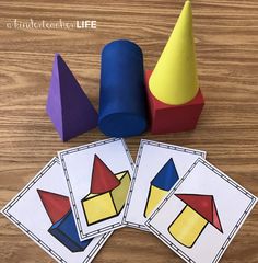 three pieces of colored paper next to two cones and one cone on a wooden table