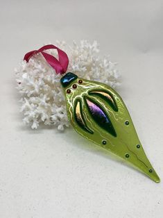 a green ornament hanging from a pink ribbon