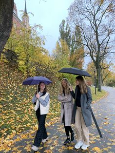 three women are walking down the street with umbrellas over their heads as they talk to each other