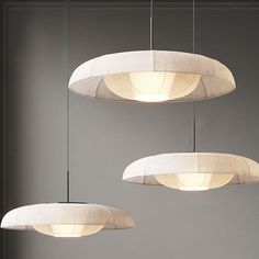 three circular lights hanging from the ceiling in a room with gray walls and flooring