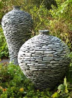 two large vases sitting in the middle of a garden