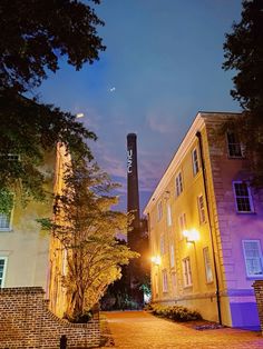 an old brick building is lit up at night with the moon in the sky behind it