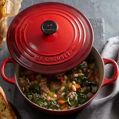 a red pot filled with soup next to bread