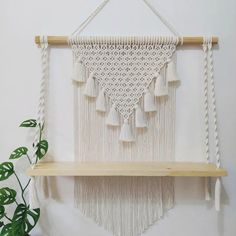 a macrame wall hanging with tassels on a shelf