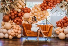 a woman sitting on a couch surrounded by balloons