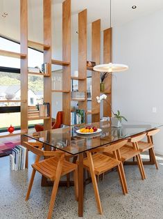 a dining room table with chairs and a bowl of fruit on top of the table