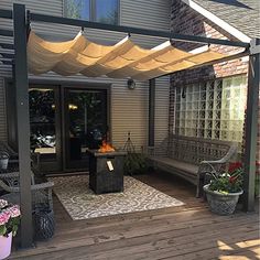 a patio covered in plants and flowers next to a building with an awning over it