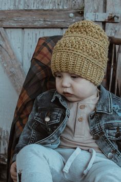 a small child wearing a knitted hat sitting in a chair