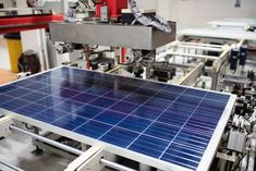 an assembly line with solar panels on the conveyor belt and machinery in the background