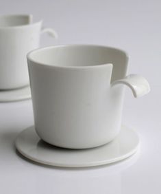 two white cups and saucers sitting on top of each other in front of a white background