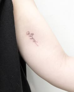 a woman's arm with a single flower tattoo on the left side of her arm