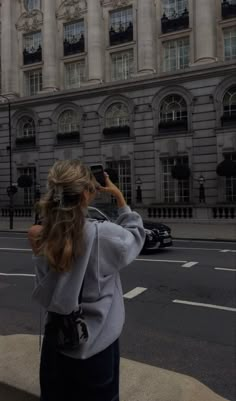 a woman is taking a photo in front of a building