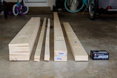 several pieces of wood sitting on the floor next to a toolbox and some bikes