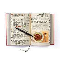 an open book with a bowl of food and a pen on top of the page