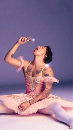 a ballerina drinking from a wine glass while sitting on the floor