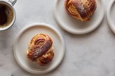 three white plates topped with pastries next to a cup of coffee