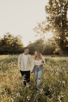 a man and woman walking through tall grass