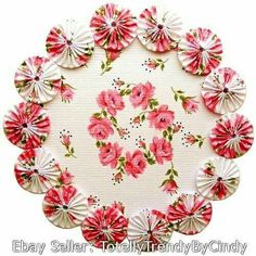 a paper doily with pink flowers and green leaves