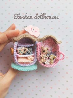 a hand holding a tiny dollhouse with clothes in it