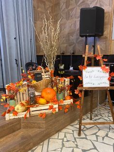 an arrangement of pumpkins and gourds on display in front of a sign