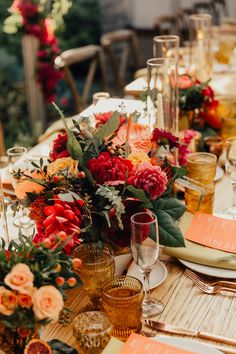 the table is set with orange and red flowers