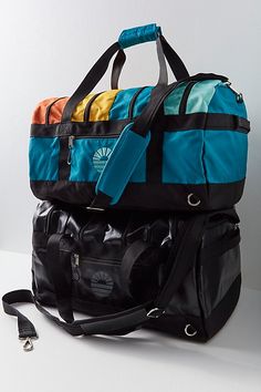 three duffel bags stacked on top of each other with one bag hanging off the side