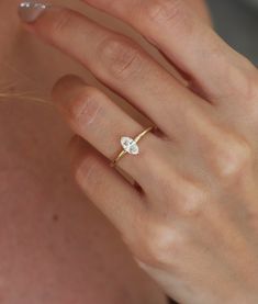 a woman's hand wearing a gold ring with a single diamond on it,