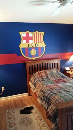 a bed room with a neatly made bed and a wall painted with the colors of barcelona