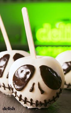 three chocolate covered apples with sticks in the shape of jack - o'- lantern faces