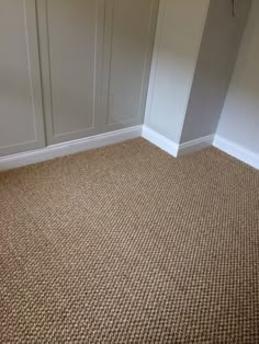 an empty room with carpeted flooring and white cupboards on the wall behind it