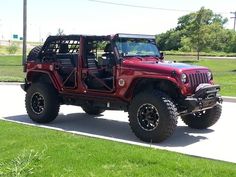 a red jeep is parked on the side of the road in front of some grass