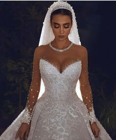 a woman wearing a wedding dress with long sleeves and beaded detailing on the shoulders