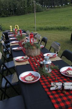 a table set up with plates and napkins for an outdoor dinner in the grass