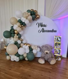 a teddy bear sitting in front of a balloon arch