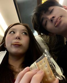 two young people are eating crackers and looking at the camera