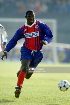 a soccer player is running with the ball in his hand and another player behind him