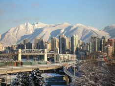 a city with mountains in the background and snow covered trees on the foreground,